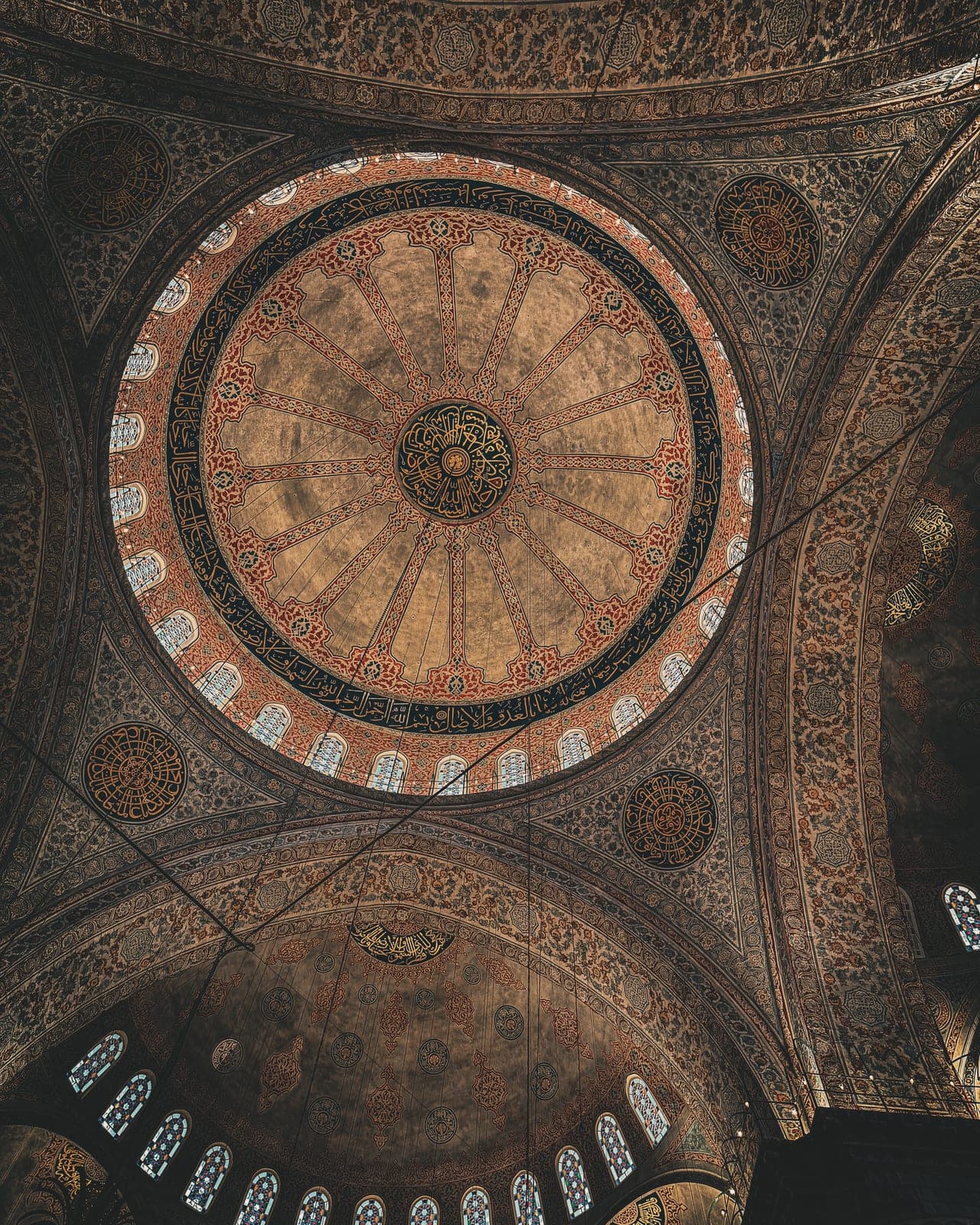 An ornate painted dome ceiling inside a mosque