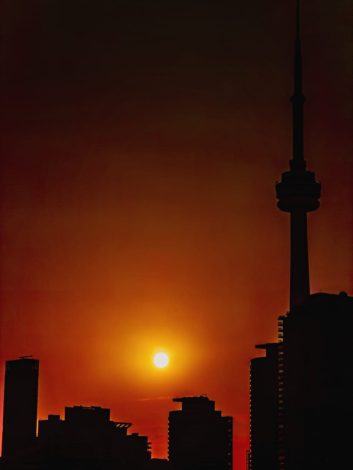 The CN Tower in silhouette against an orange sunset