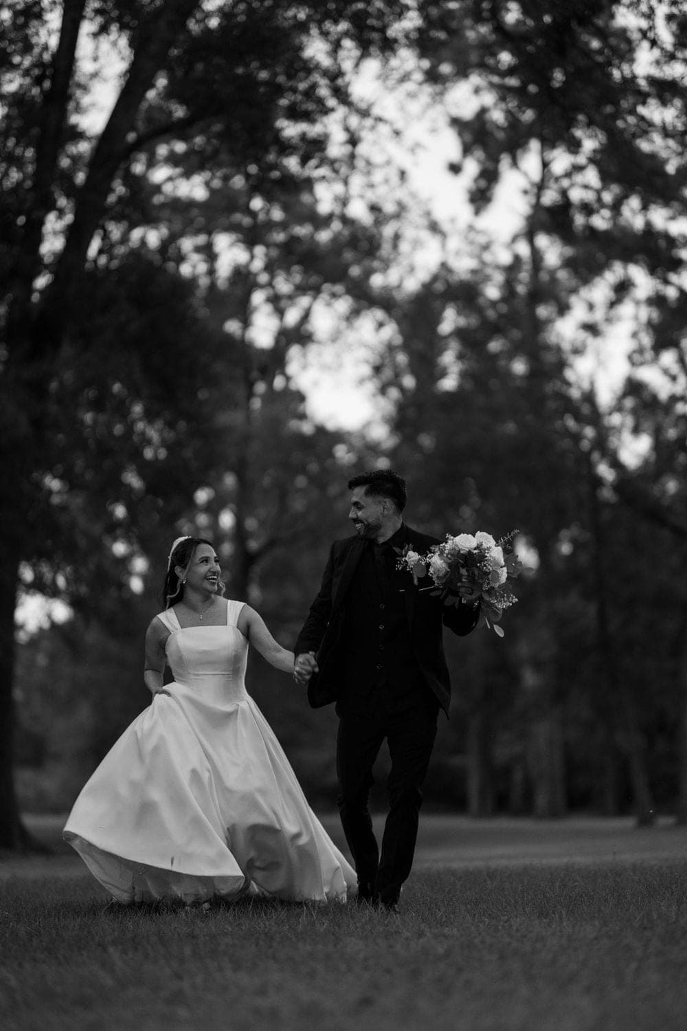 A couple walking through trees, in black and white